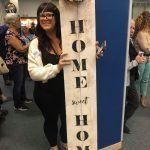 A woman is holding a sign that says `` home sweet home ''.