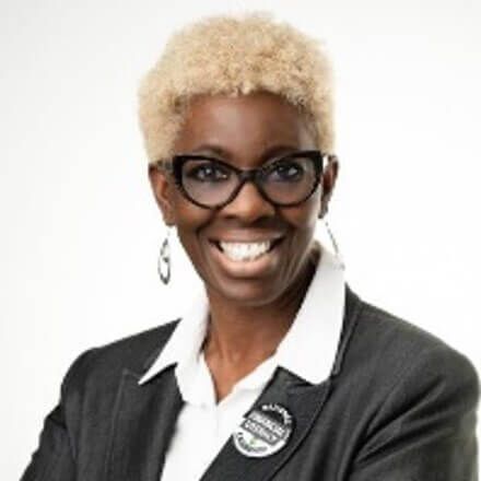 A woman wearing glasses and a black jacket is smiling for the camera.