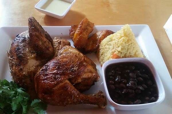 A plate of food with a chicken , rice and beans on a table.