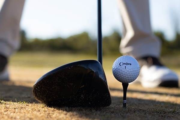 A golf ball is on a tee next to a golf club.