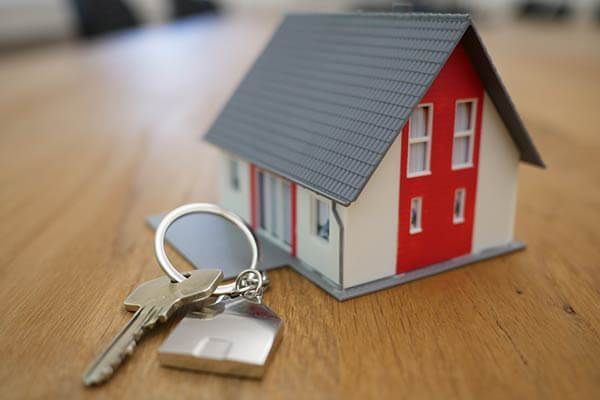 A model house and keys are on a wooden table.