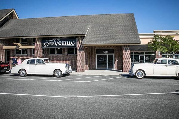 Two white cars are parked in front of a building.