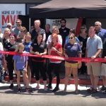 A group of people are standing in front of a red ribbon.