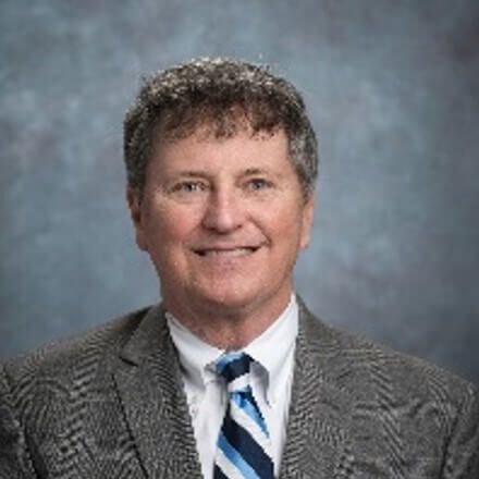 A man in a suit and tie is smiling for the camera.