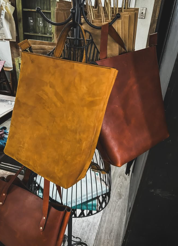 Hanging leather bags in mustard yellow and brown on a shop display rack