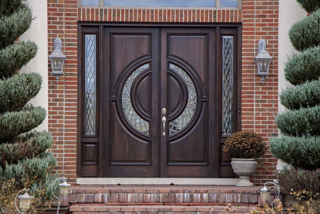 A wooden door with a carved design on it is against a gray wall.