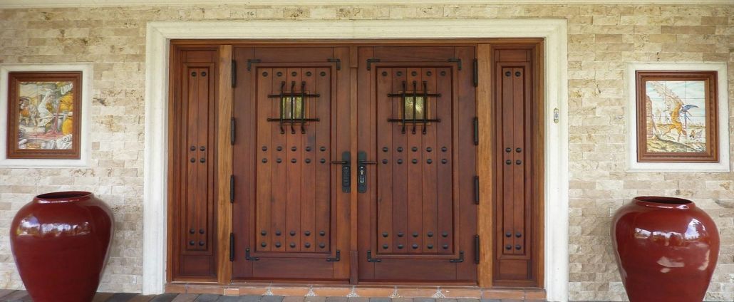 A large wooden door with two red vases in front of it.