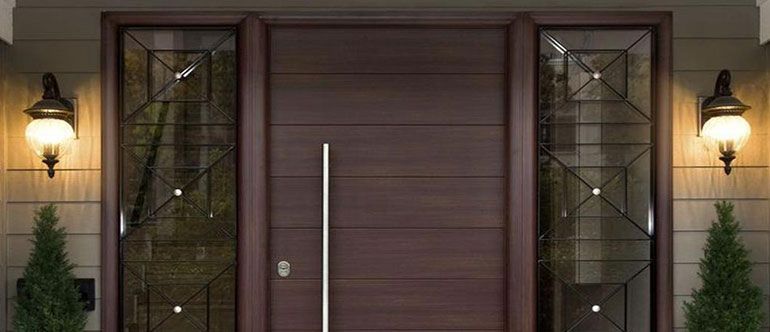 The front door of a house with a large wooden door and glass windows.