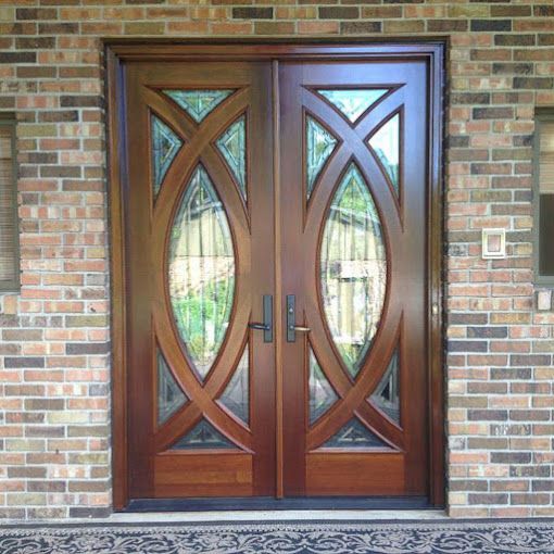 A pair of wooden doors with stained glass on a brick wall.