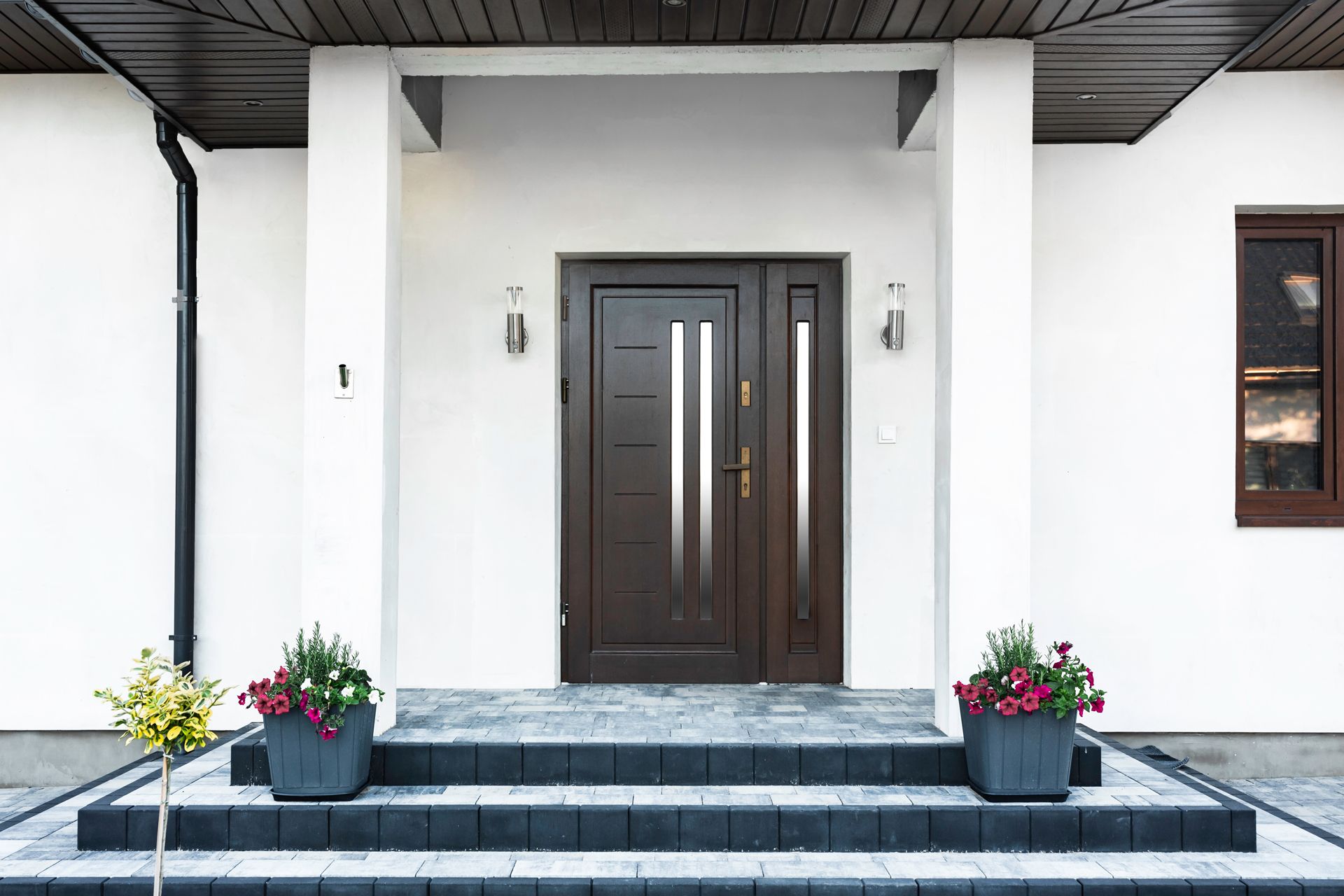 The front door of a white house with a wooden door and steps.