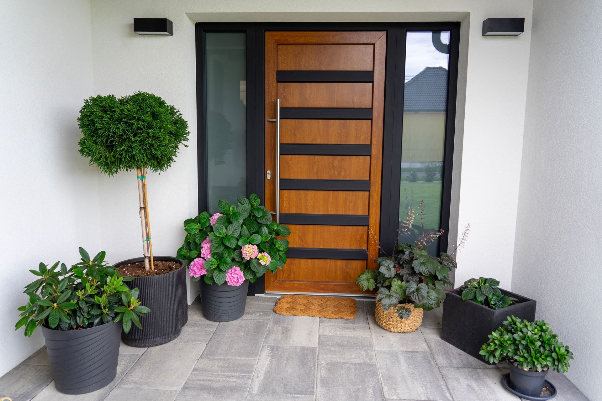 A wooden door is surrounded by potted plants and flowers.