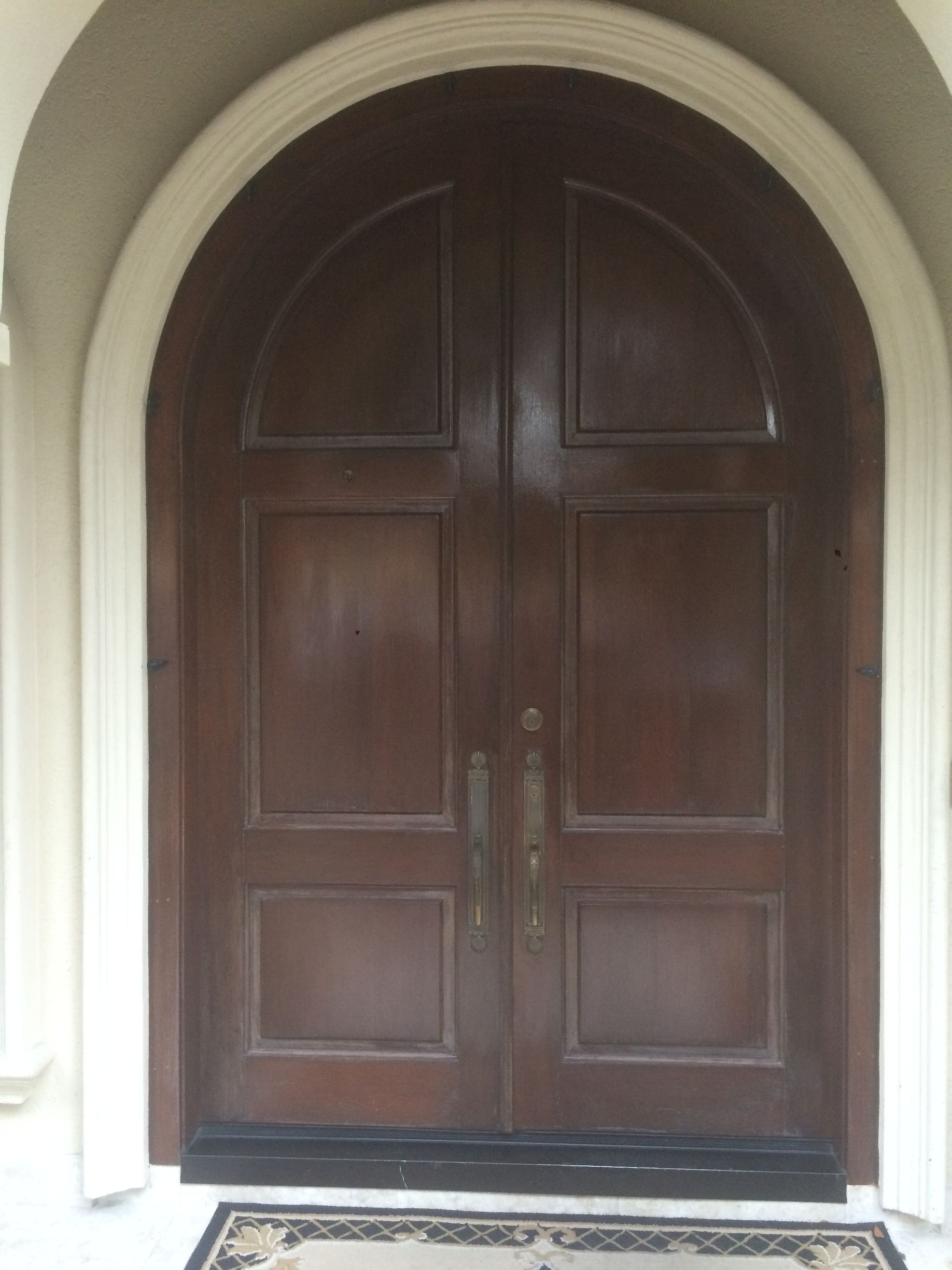 A large arched door with a rug in front of it