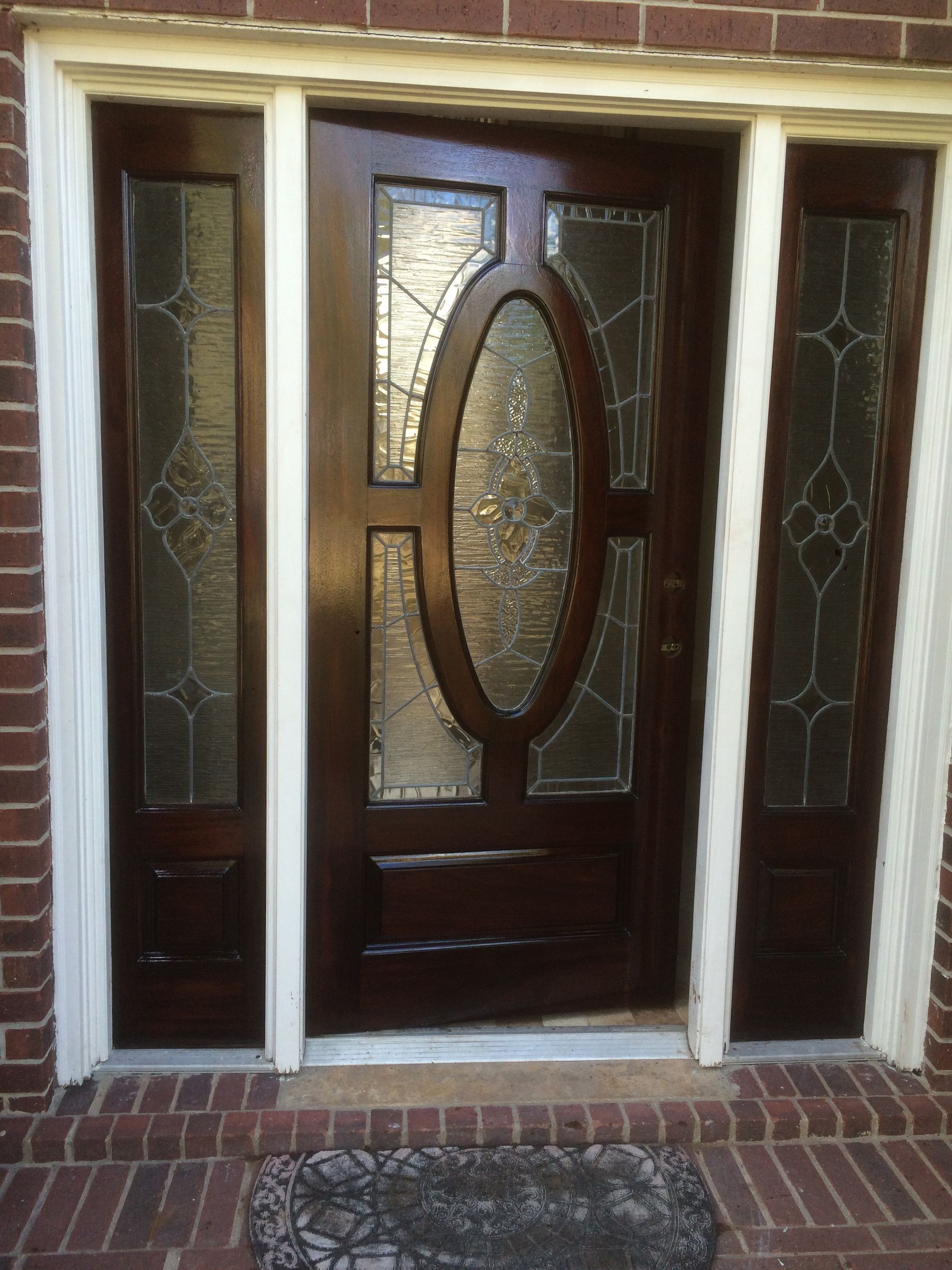 The front door of a brick house has a stained glass window