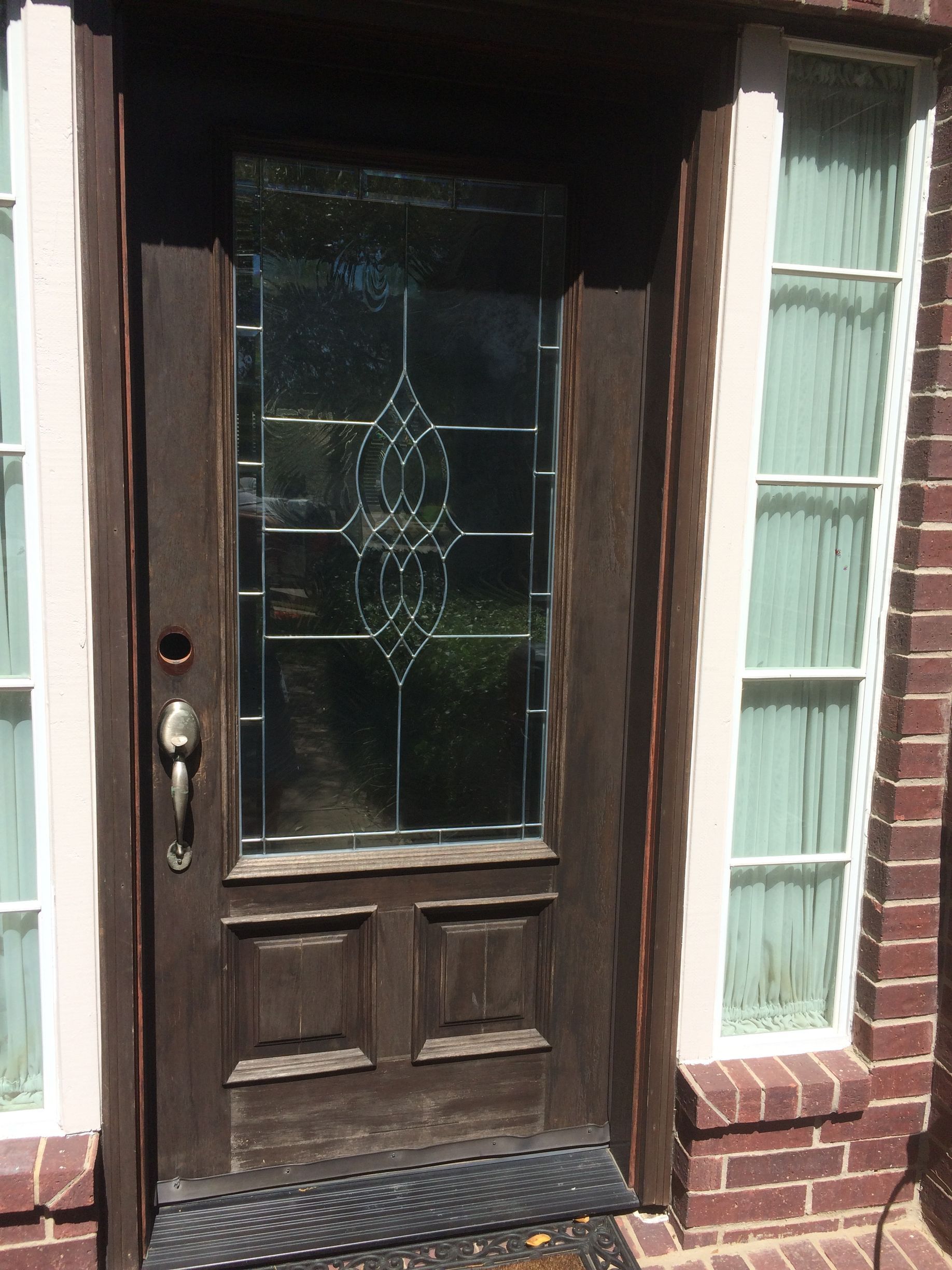 A brown door with a stained glass window on a brick building