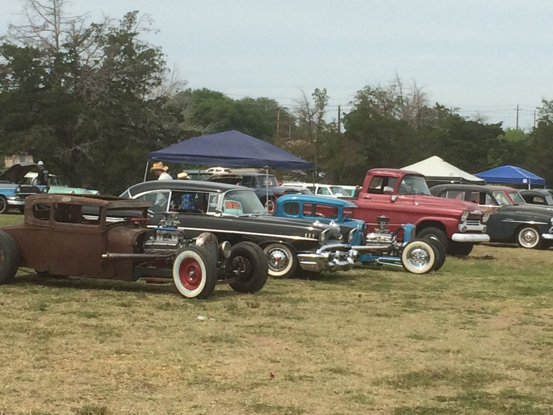 A row of old cars are parked in a grassy field