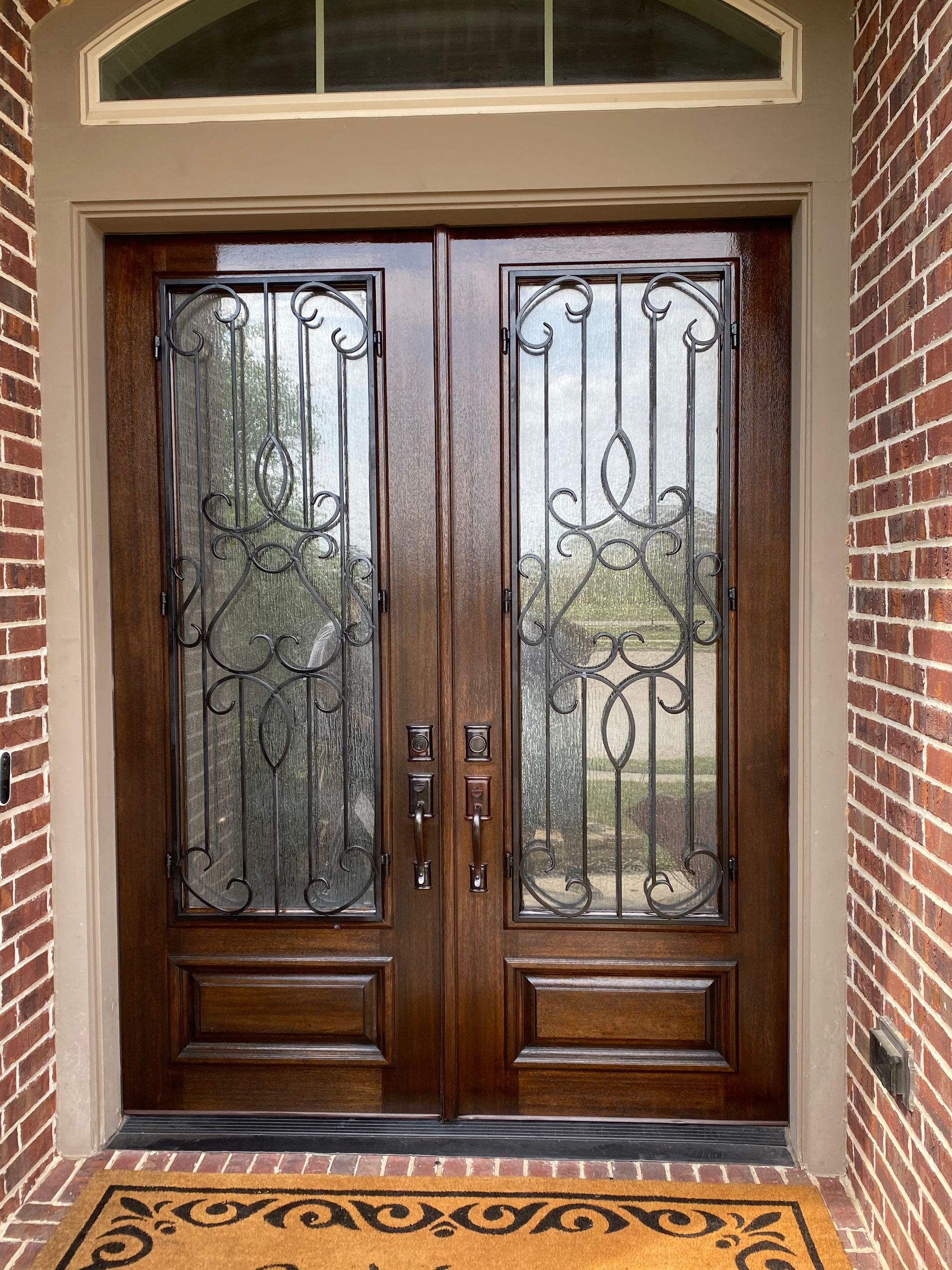 A brick building with a wooden door and a wrought iron door.