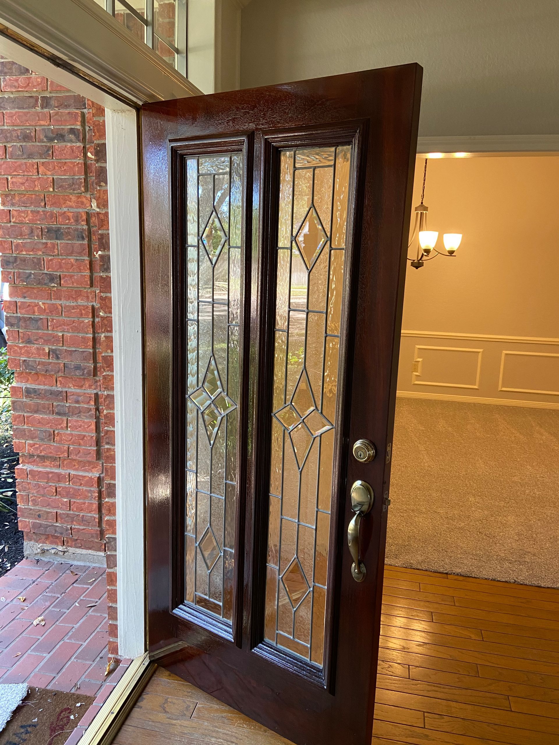 A door with a stained glass window is open in an empty room.