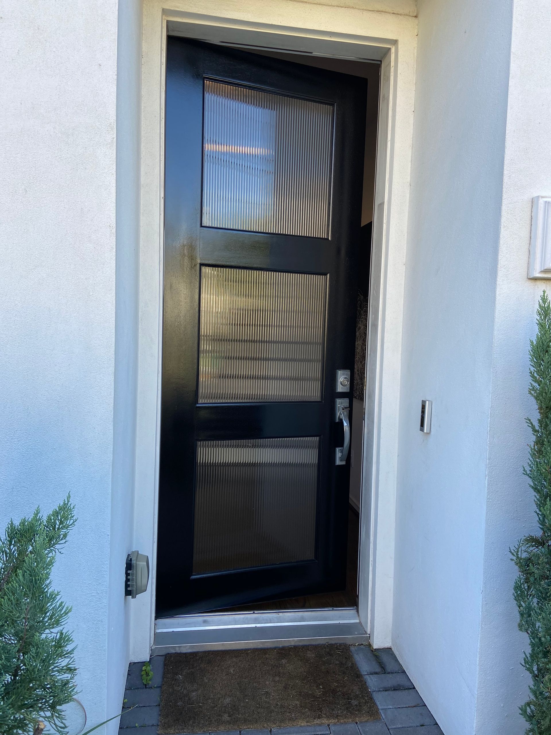 A black door is open to a white house