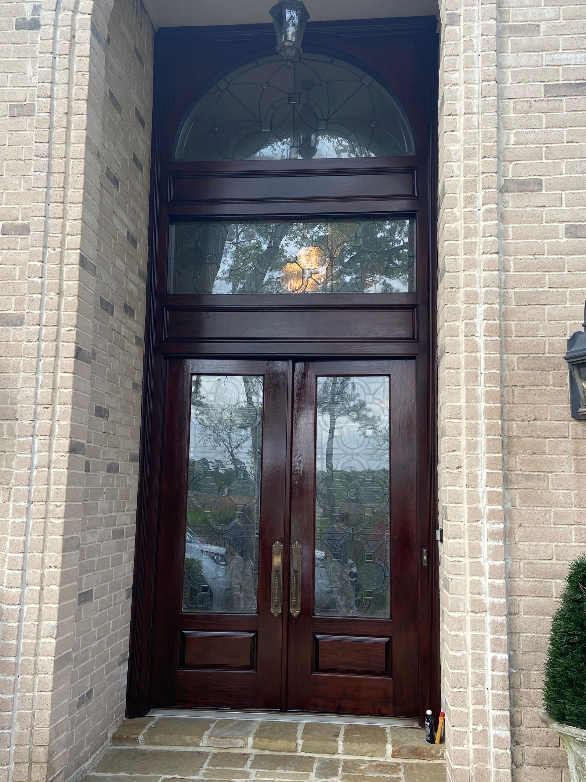 The front door of a brick building with a wooden door and glass windows.