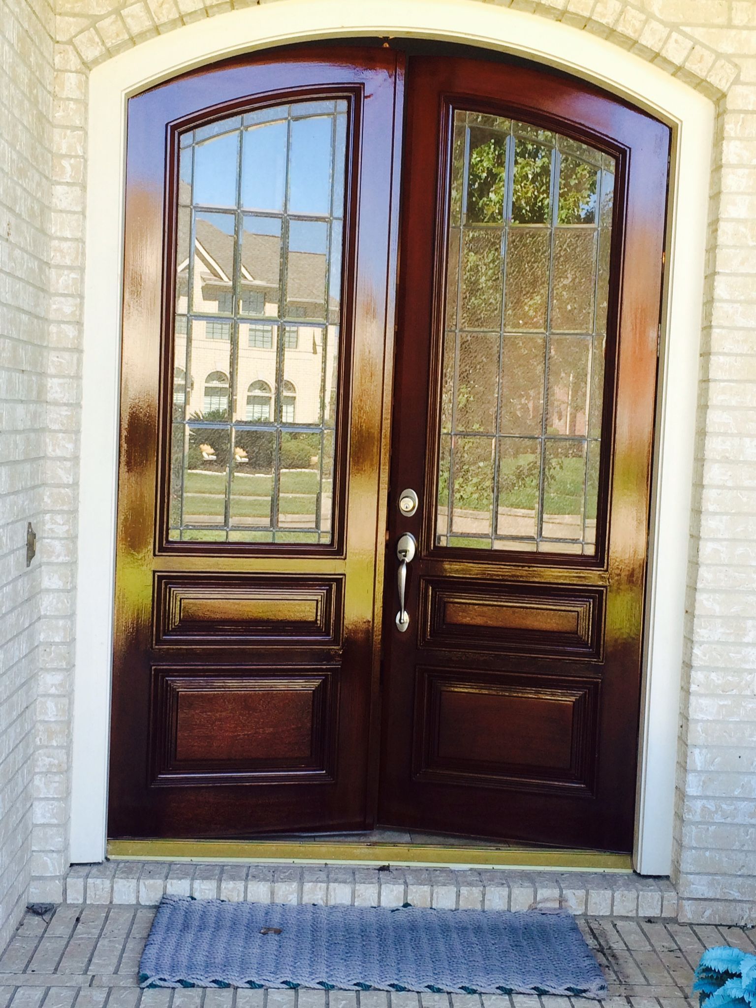 A door with a stained glass window is painted dark brown