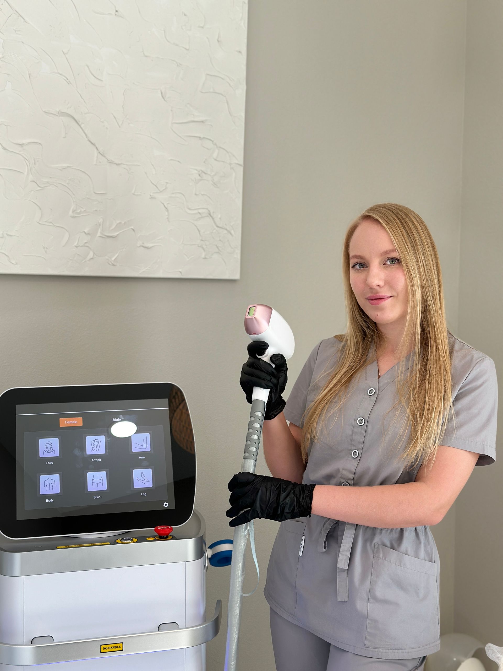 A woman is standing in front of a machine holding a device.