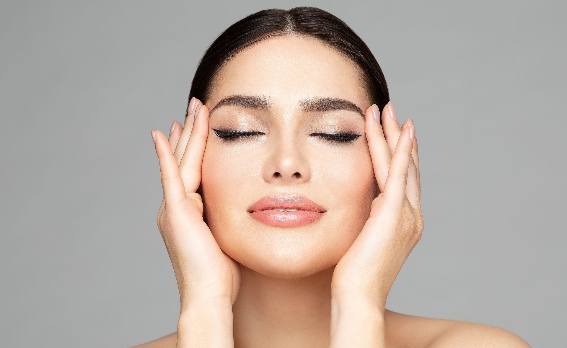 A person's eyebrow is being shaped with a tool, their eye is visible, with a person's hand in a black glove.