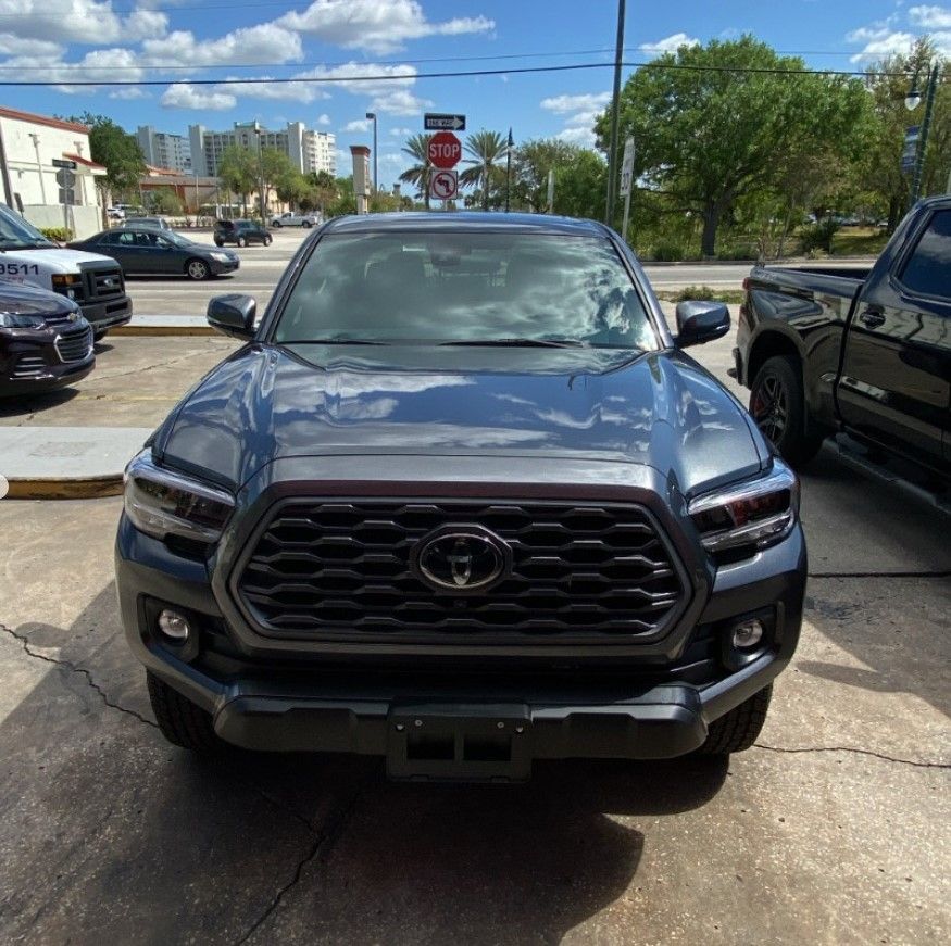 Man in blue uniform wiping a dark blue car with a sponge. Car appears to be in a garage.
