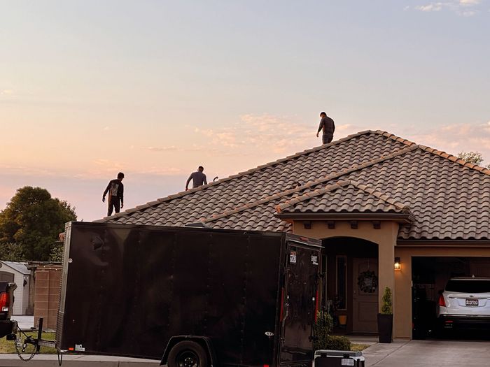 Two men are working on the roof of a house.