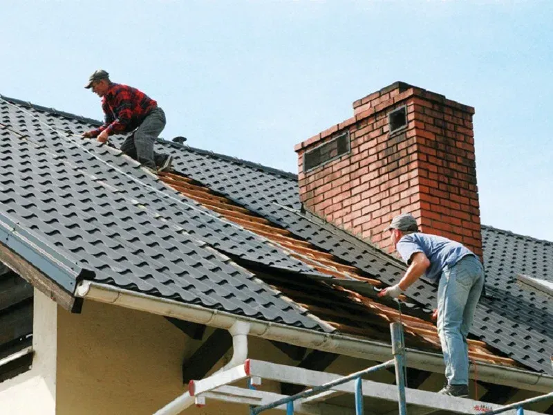 Two men are working on the roof of a house.