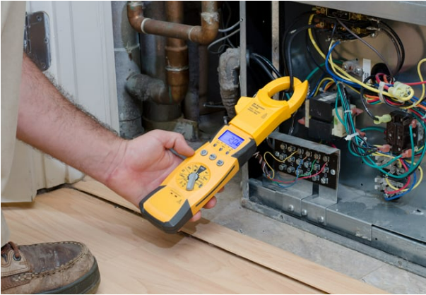 A man is holding a clamp meter in front of an air conditioner.