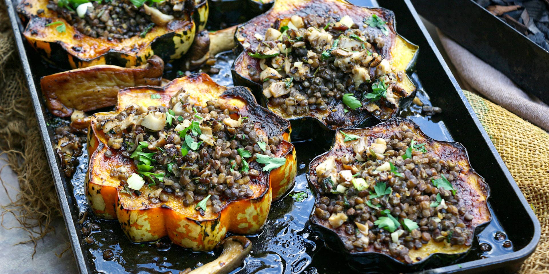 Grilled maple smoked acorn squash with mushroom lentils on a pan