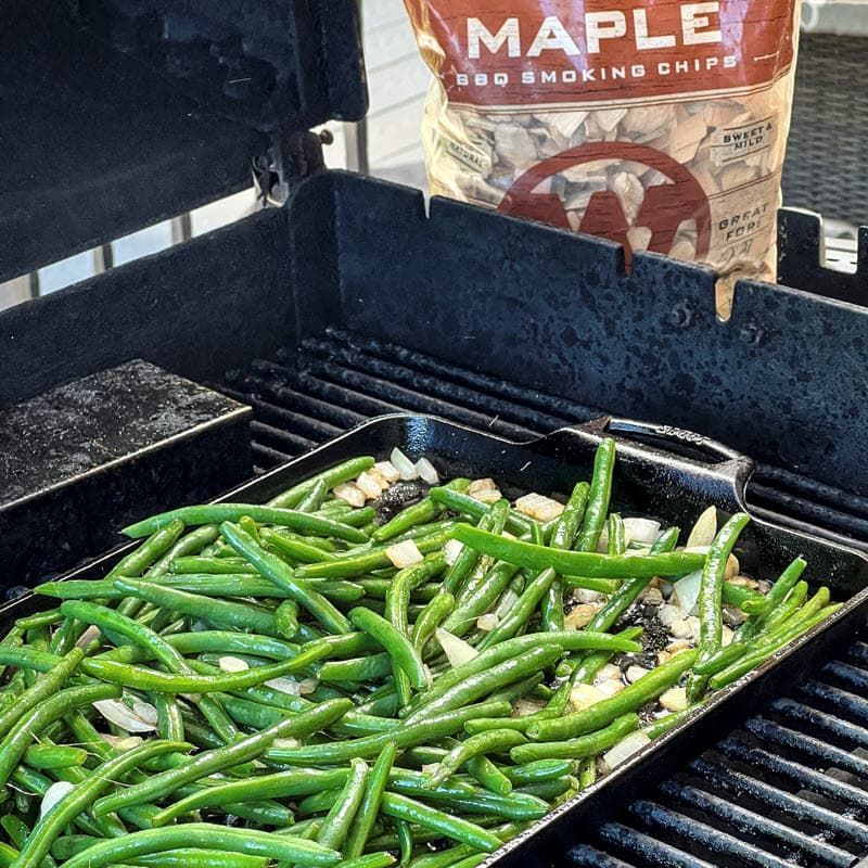 Green Beans cooking in pan on grill with smoker box and bag of Maple Smoking chips