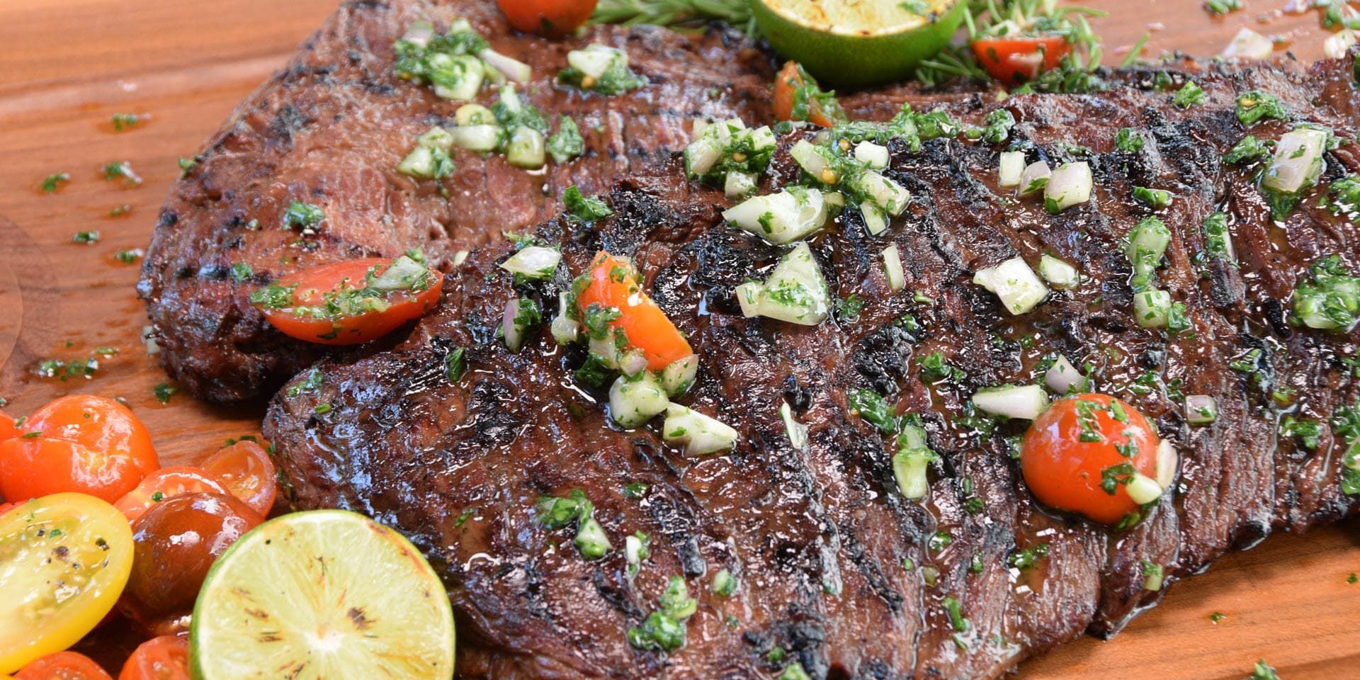 Grilled steak topped with fresh herbs, tomatoes, and lime.