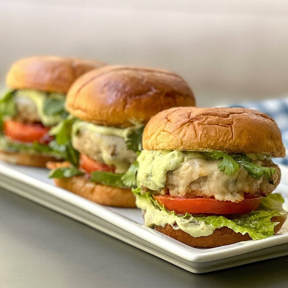 Chicken burgers with guacamole, lettuce and tomatoes