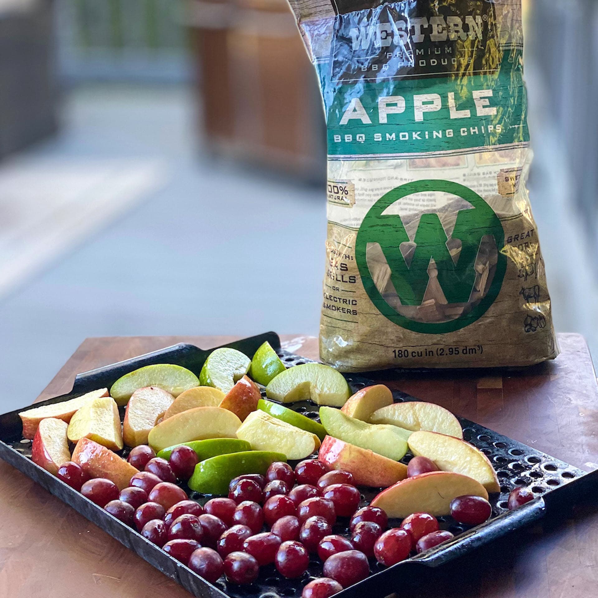Grapes and sliced apples on grill plate with bag of Western Apple BBQ Smoking Chips