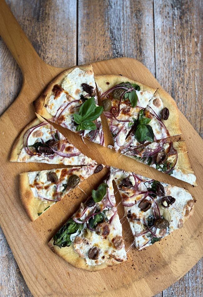 Greek Veggie Smoked Pizza on a wooden pizza peel