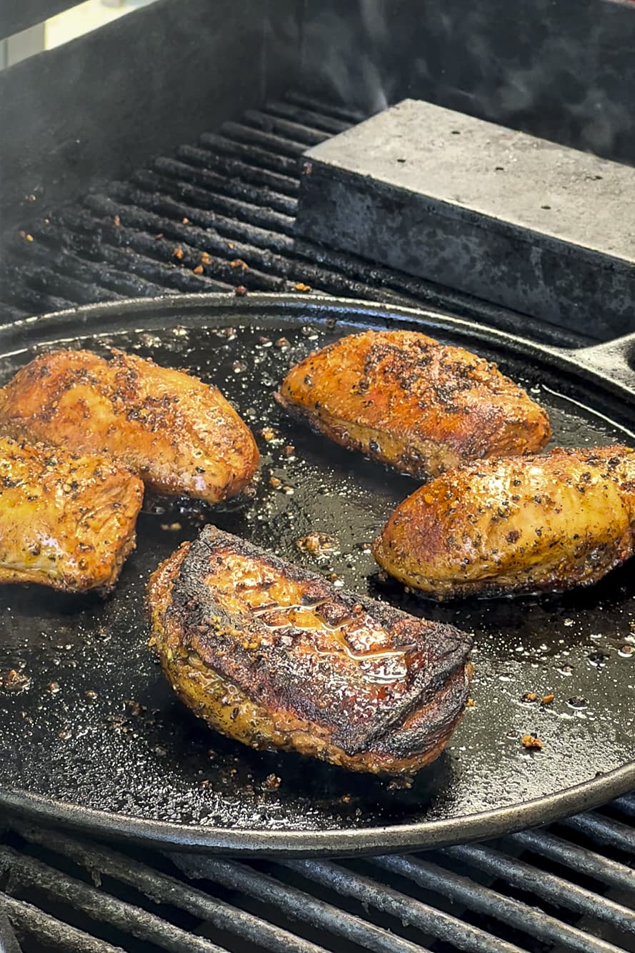 Seasoned and charred duck breast on plancha over grill