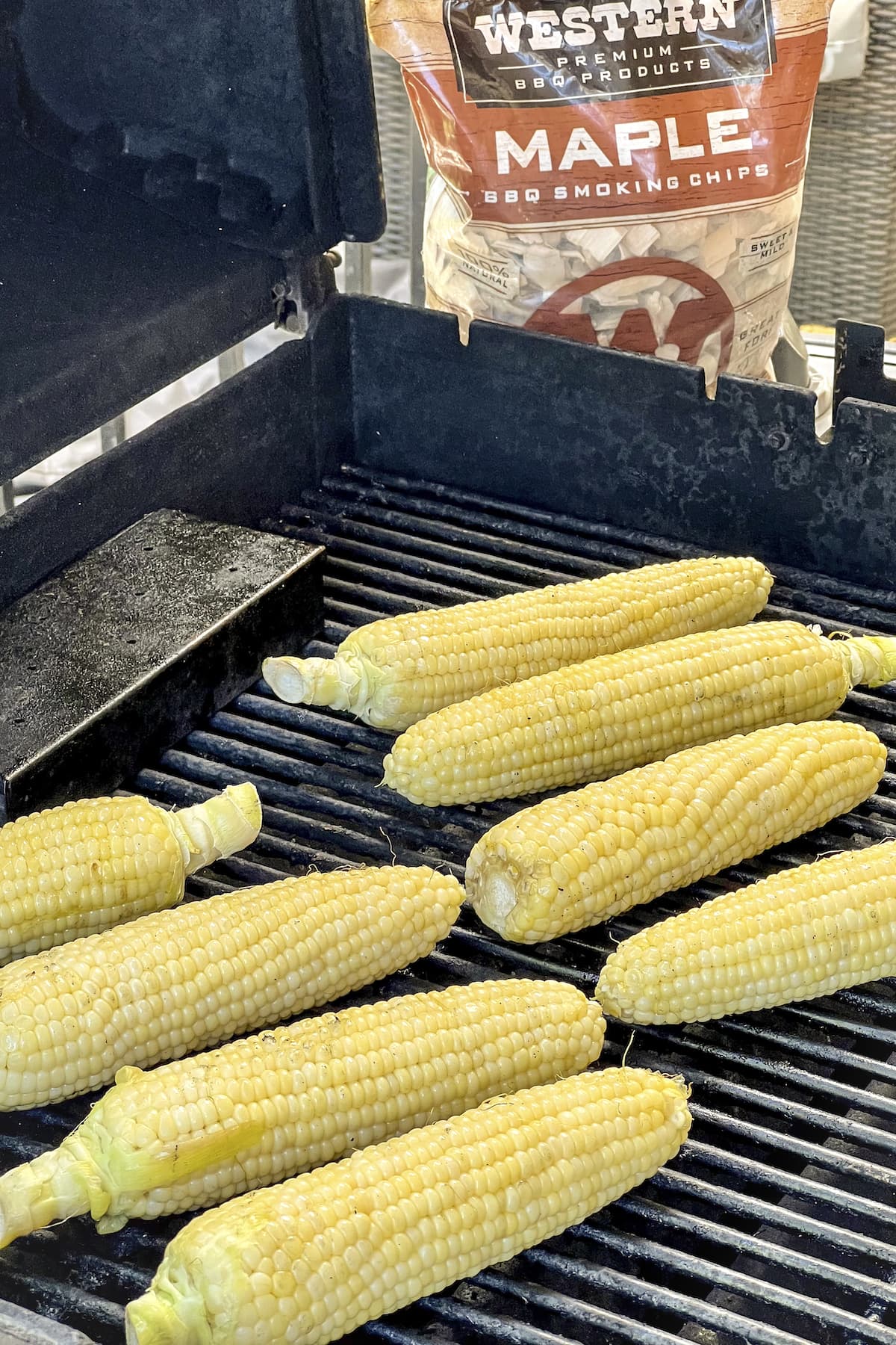 corn on the cob cooking on the grill with bag of maple bbq smoking chips