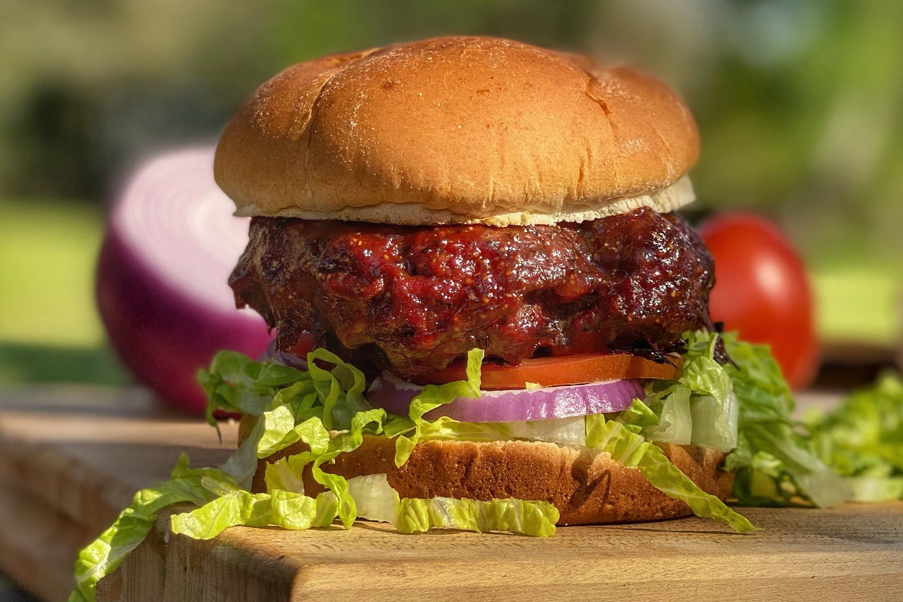Large burger  on a bun garnished with lettuce, tomato and red onion