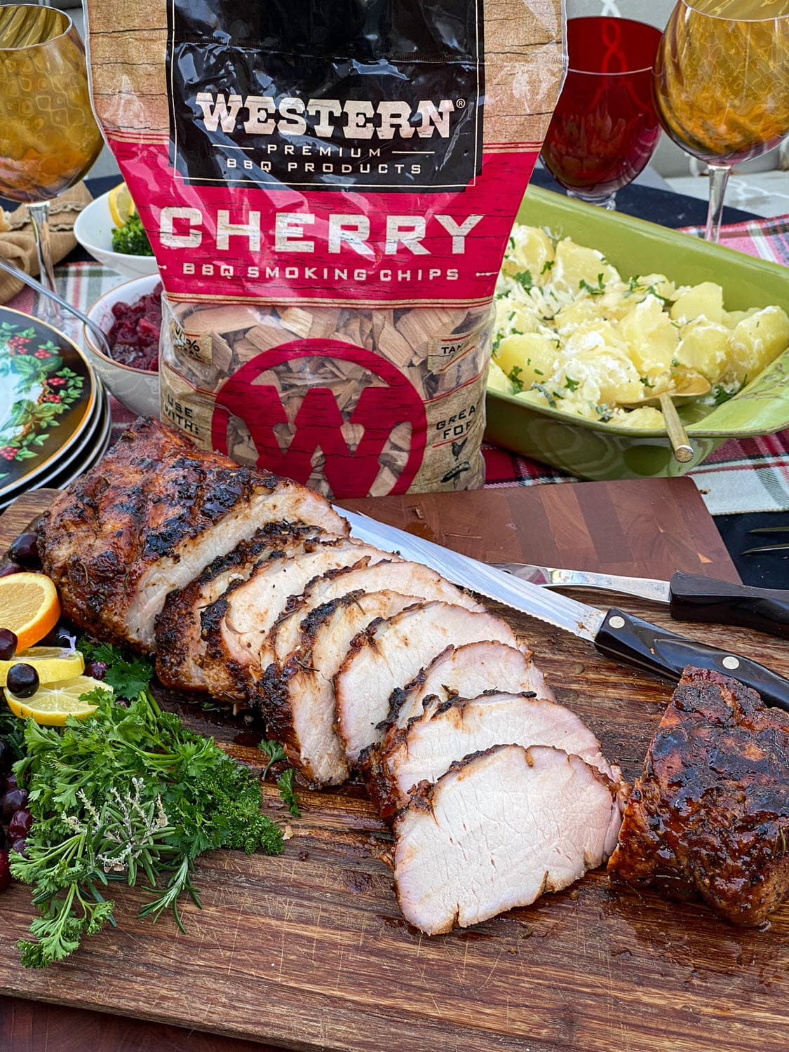Pork loin sliced on board with garnish and cherry chips bag in background