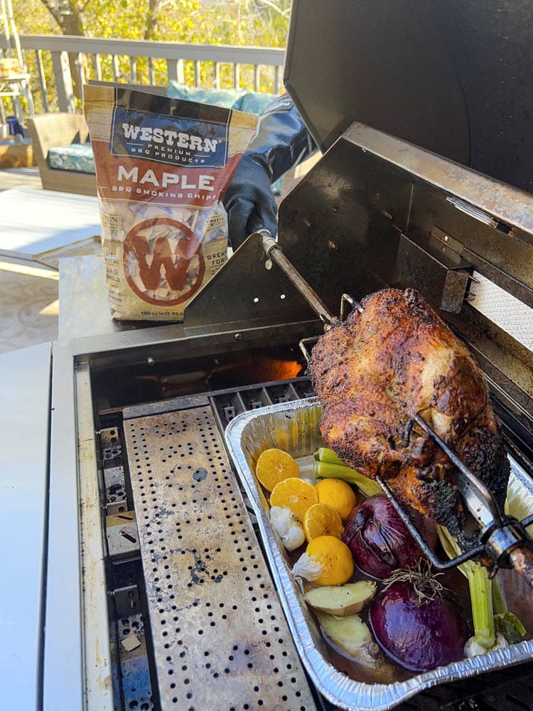 whole duck on rotisserie grill with bag of Western Maple smoking wood chips