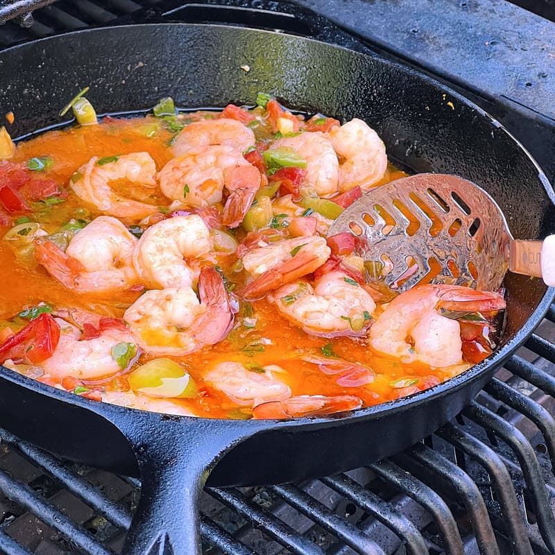 shrimp scampi poaching in butter in cast iron pan on grill