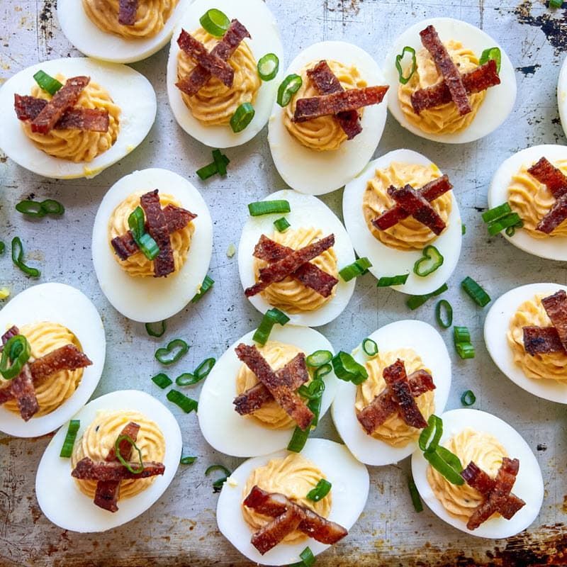 Smoked deviled eggs garnished with bacon bits and green onion