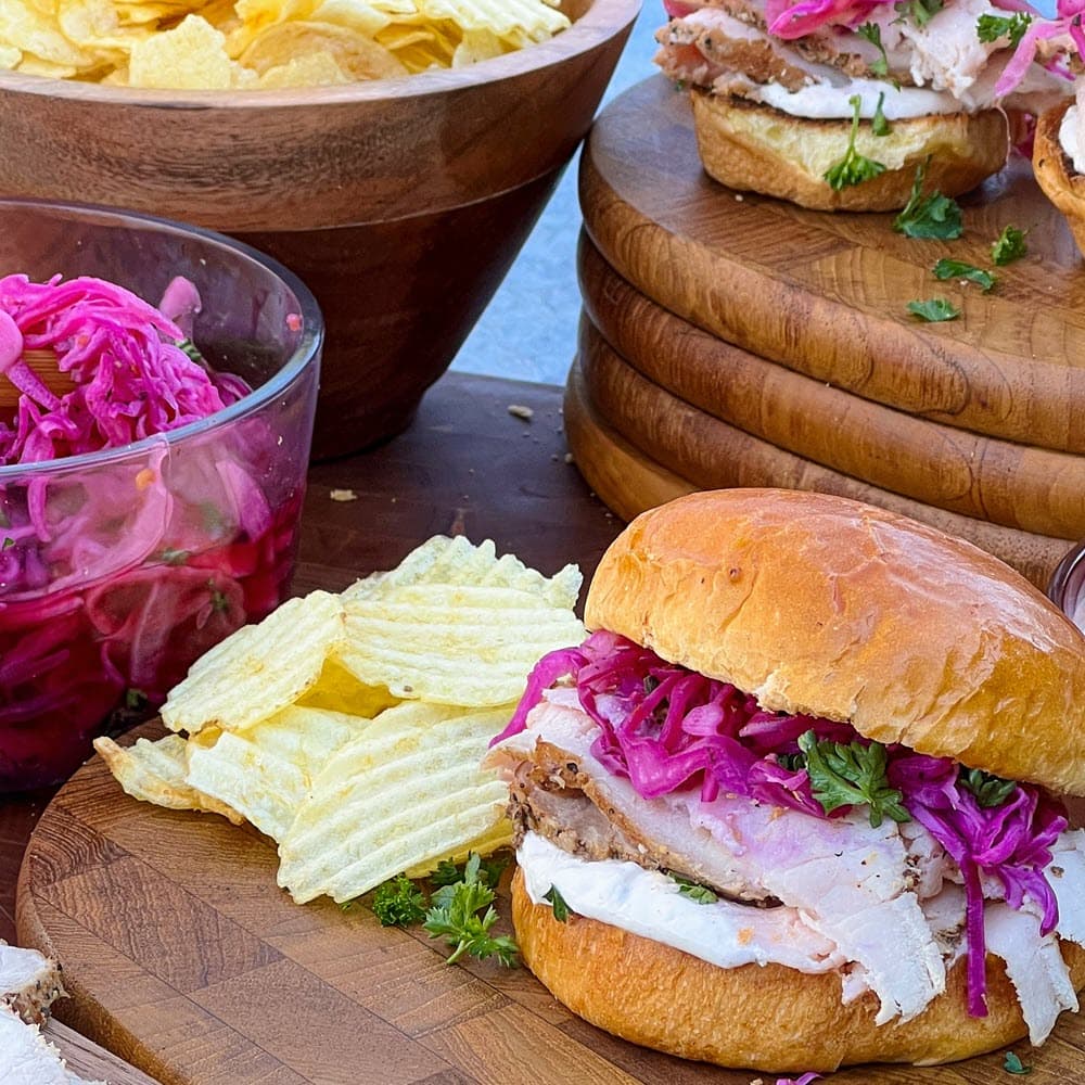 Hickory Smoked Pork Loin Sandwiches on wood plates with potato chips