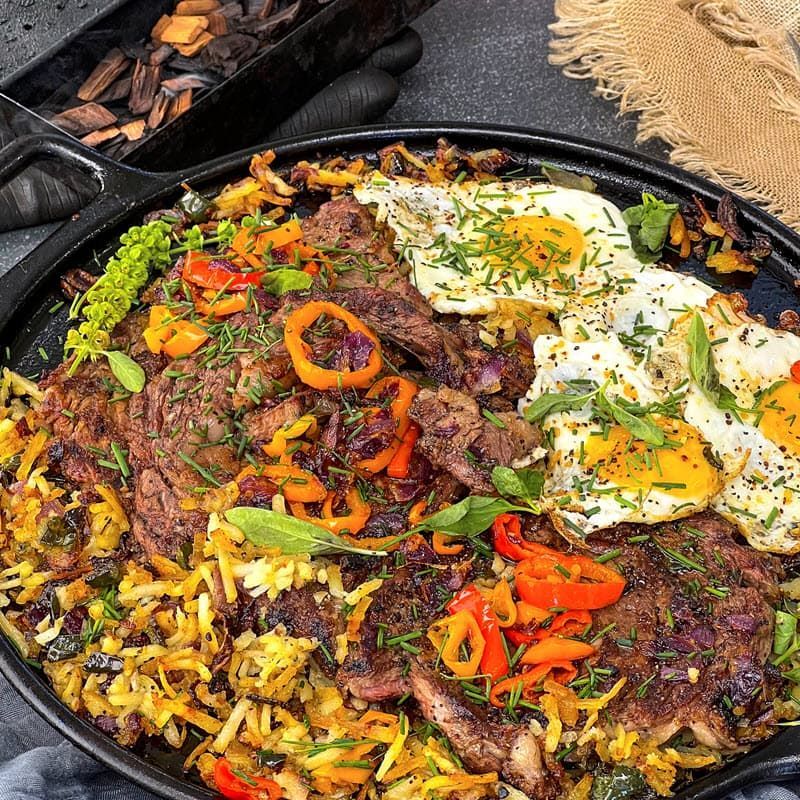 Steak and eggs over a bed of hash browns in a skillet
