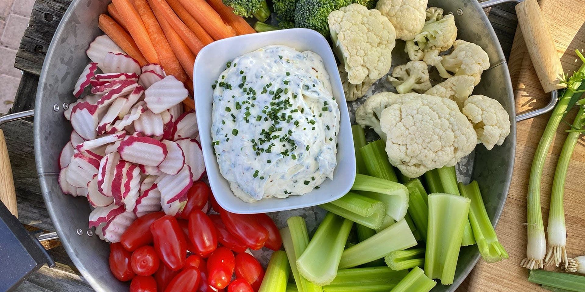 A plate of vegetables with a bowl of smoked vegetable dip on top.