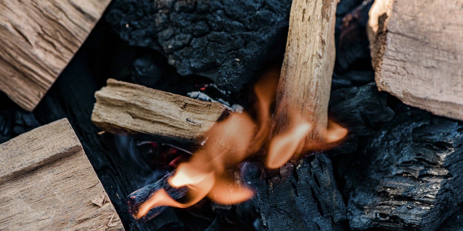 A close up of a fire with wood chunks and charcoal.