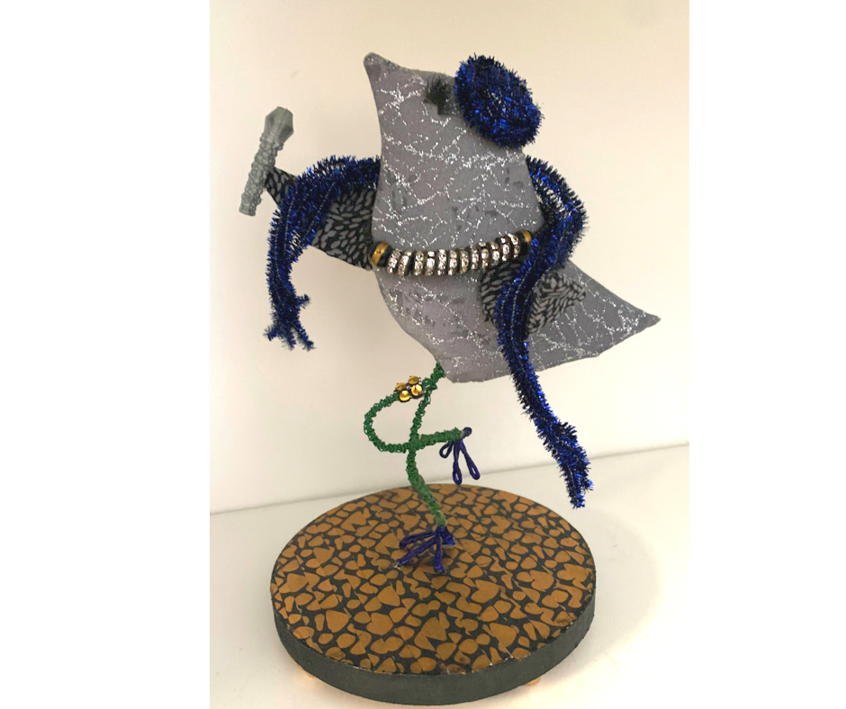 Sculptural bird figure, gray body, blue beaded arms, green leg, gold and white beaded accents, brown base. By Mary Berry - Art