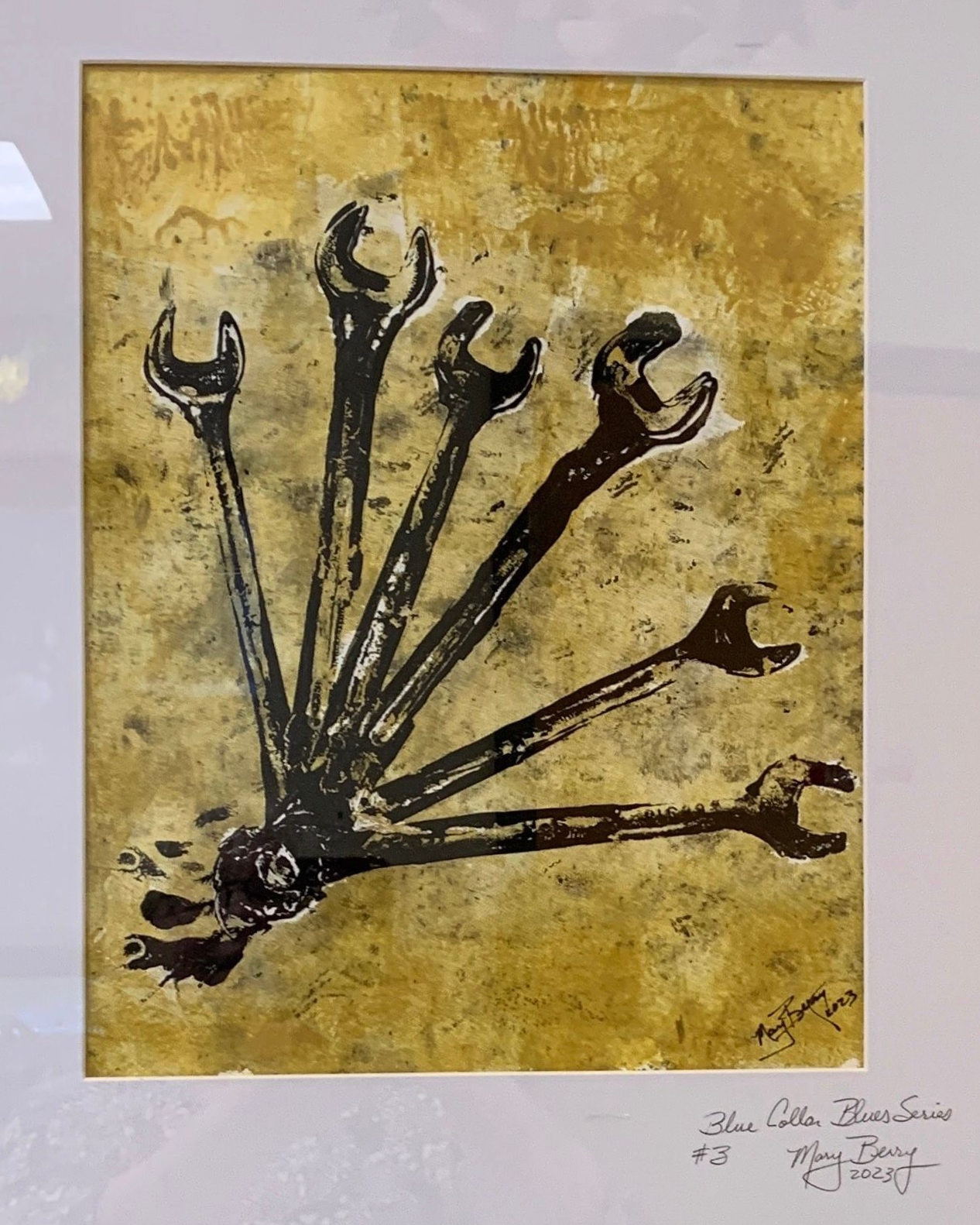 Black wrenches radiate from a central point on a golden-hued background.  By Mary Berry - Art