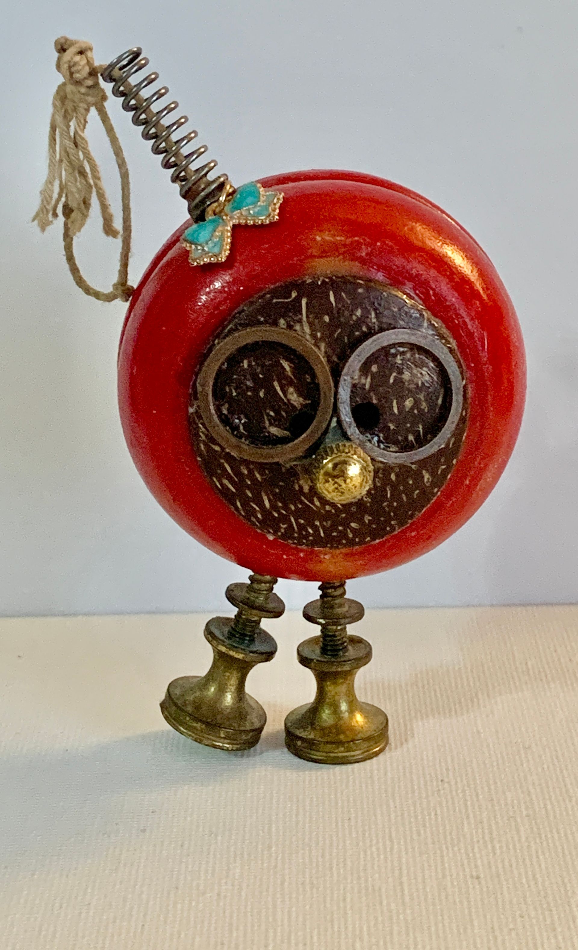 Steampunk-style robot sculpture with red head, coconut shell face, brass legs, and spring antenna.By Mary Berry - Art
